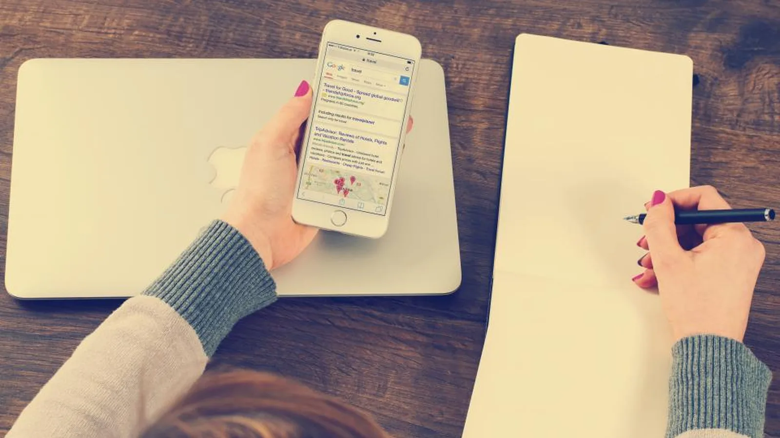 Hands holding a smartphone showing a message thread beside a notepad
