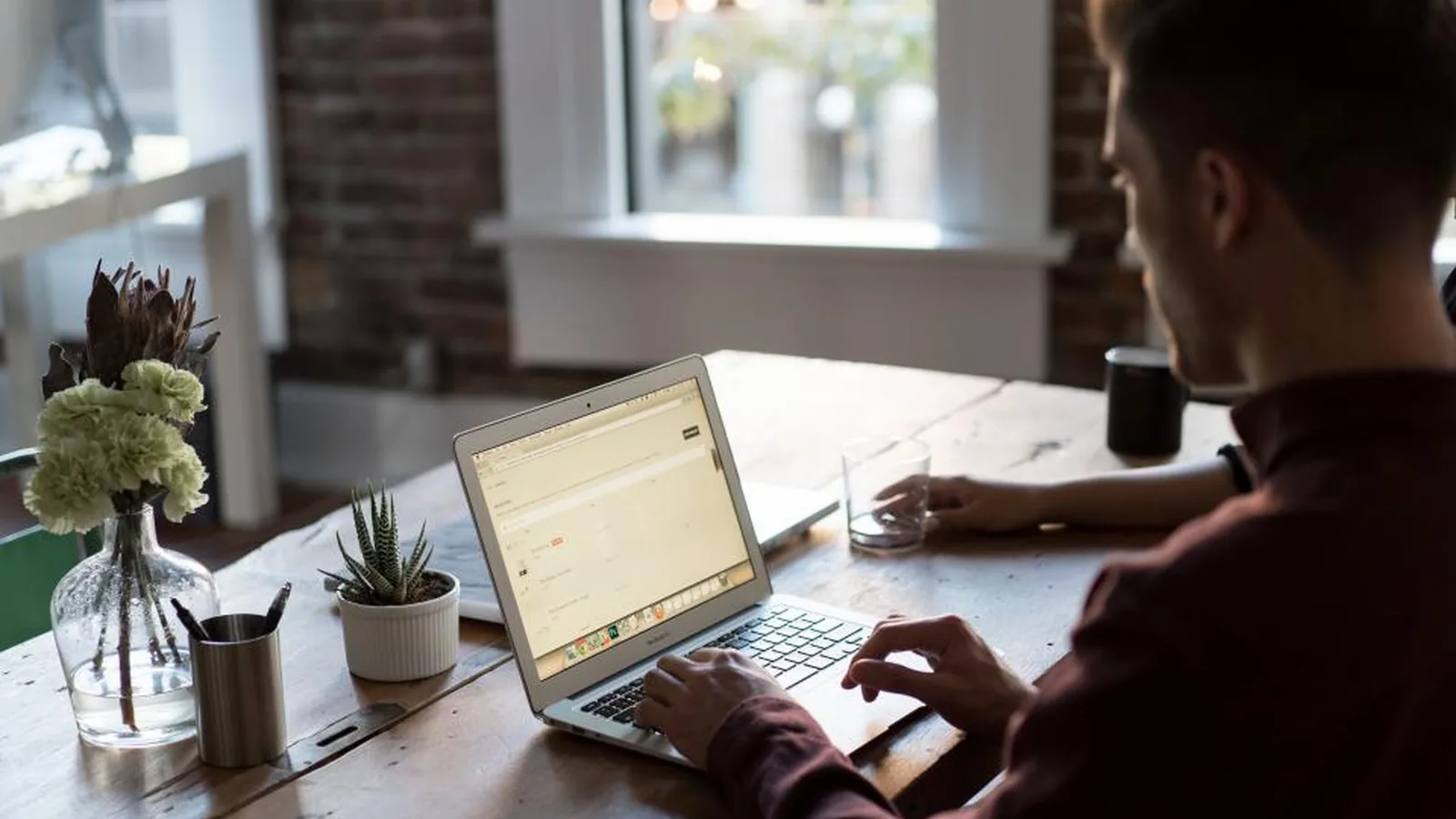 A person working at a laptop beside a window