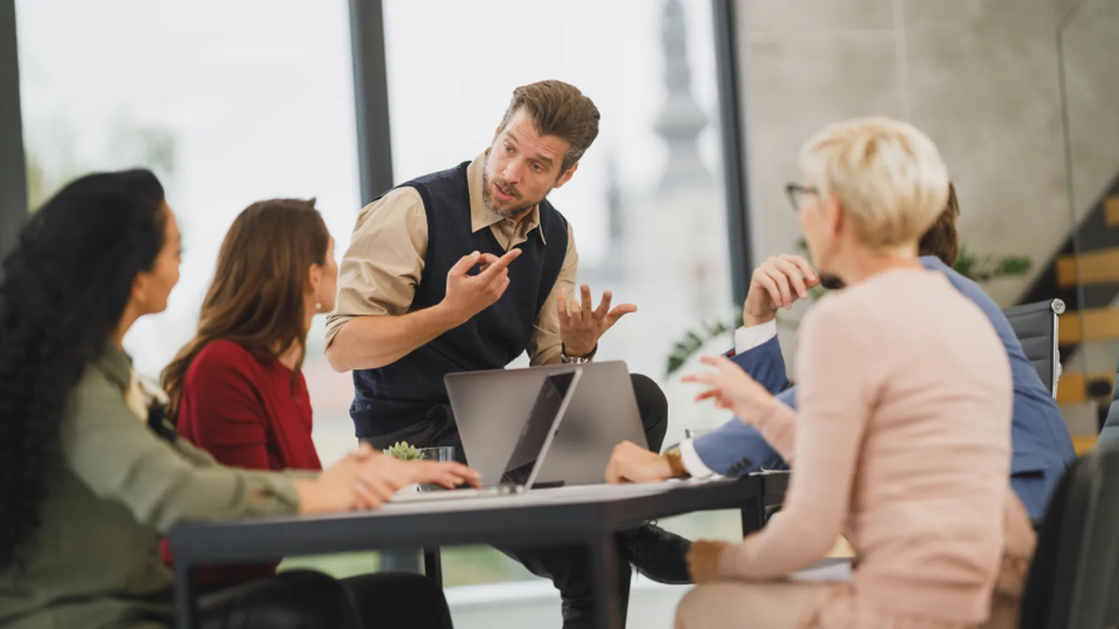 A small team talking around a table with a laptop open